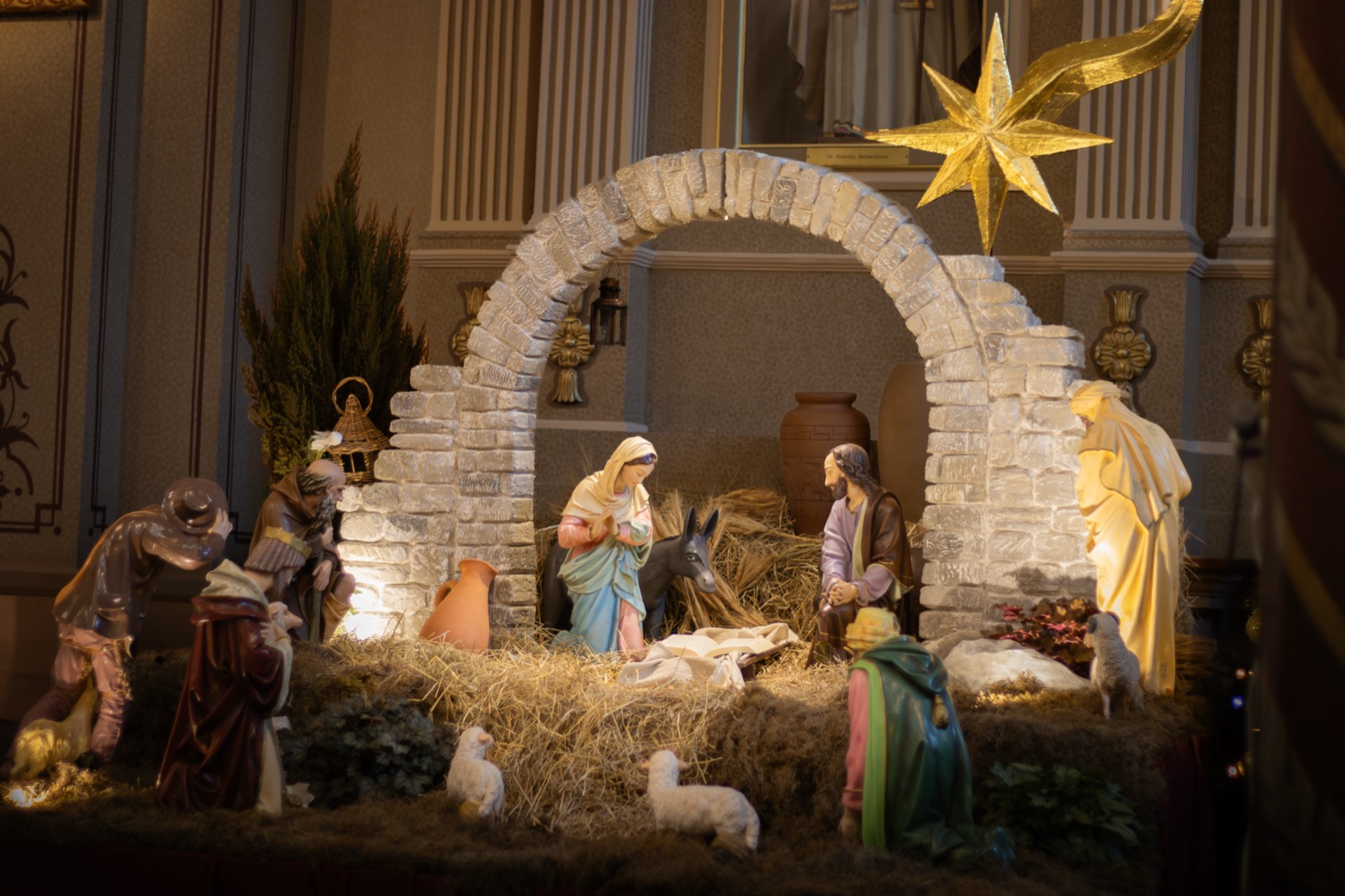 A nativity scene beneath a white stone arch crowned with a golden star.