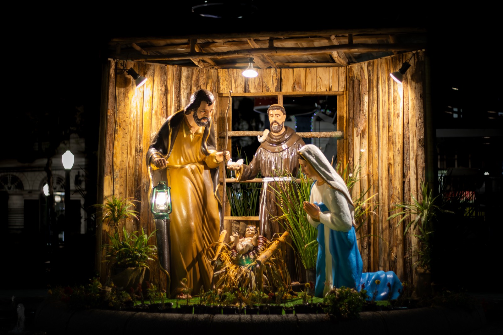 A warmly lit nativity scene inside a wooden stable at night.