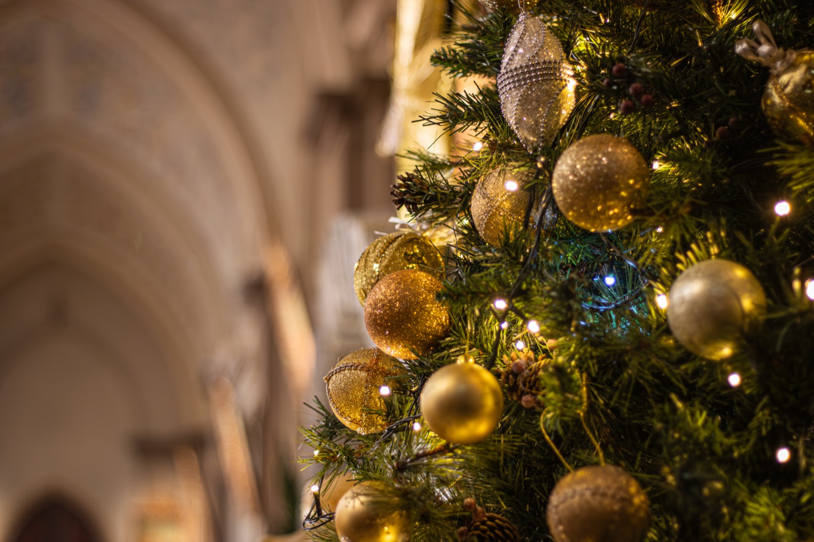 A Christmas tree with golden baubles glowing inside a church.